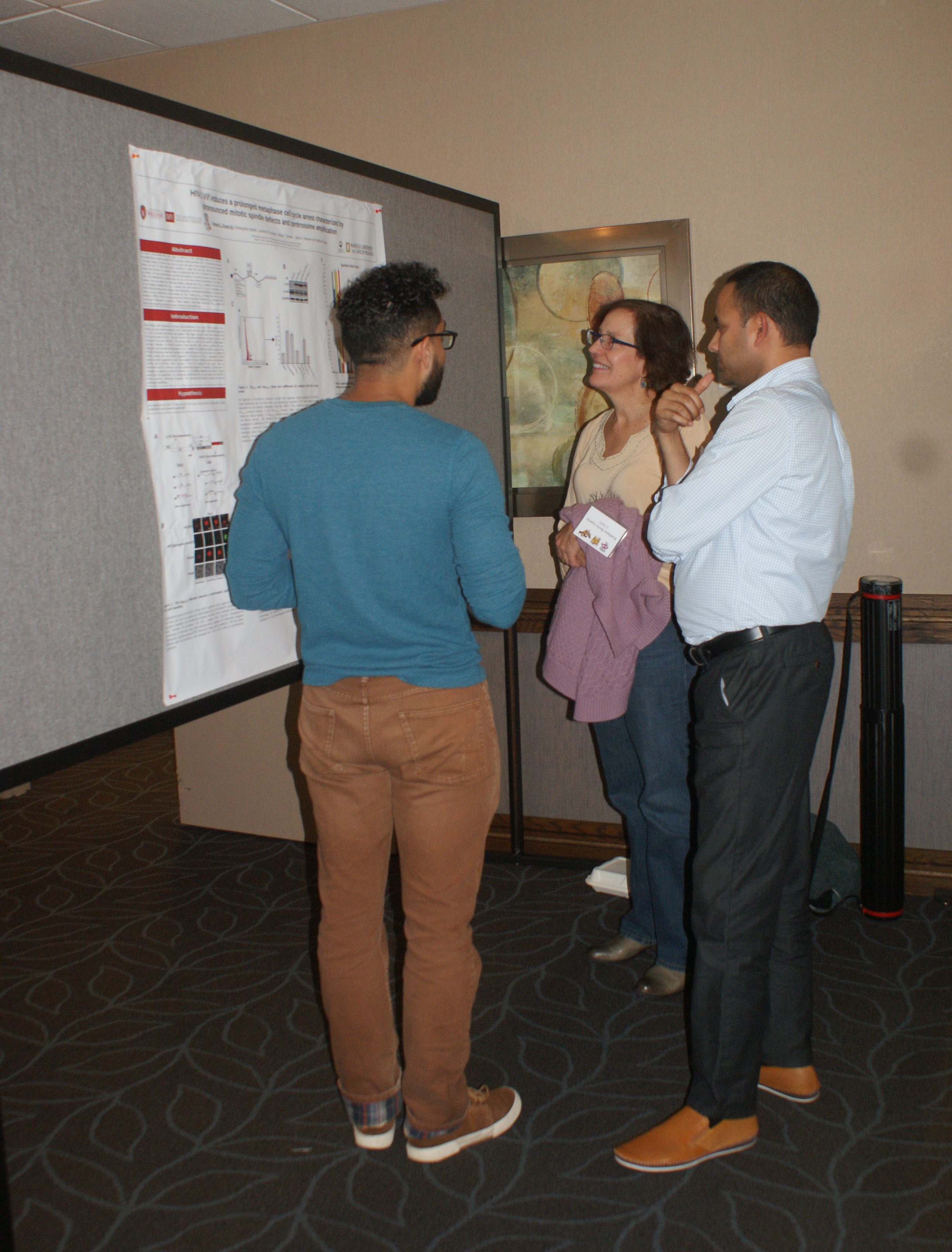 A student presenting a scientific poster to two people